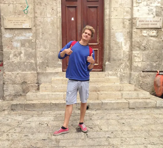 Alex as a student, standing in front of an old stone building
